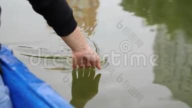 女人的手轻轻地抚摸着湖面上的绿水。 快乐的女孩慢慢地牵着她的手在水上。 靠近女人的手